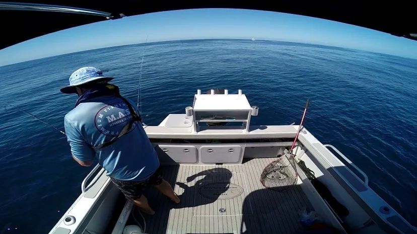 Angler standing on the rear deck beside a bait board