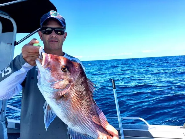 Angler holding a large pink fish beside the boat canopy