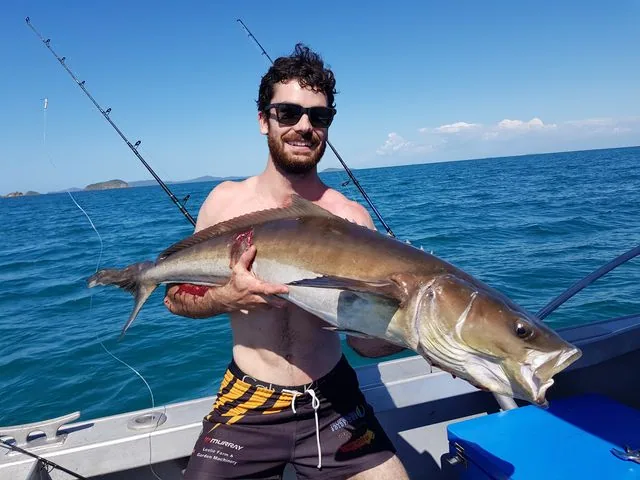 Angler holding a long brown fish aboard a boat