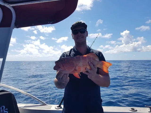 Angler displaying an orange fish on the rear deck