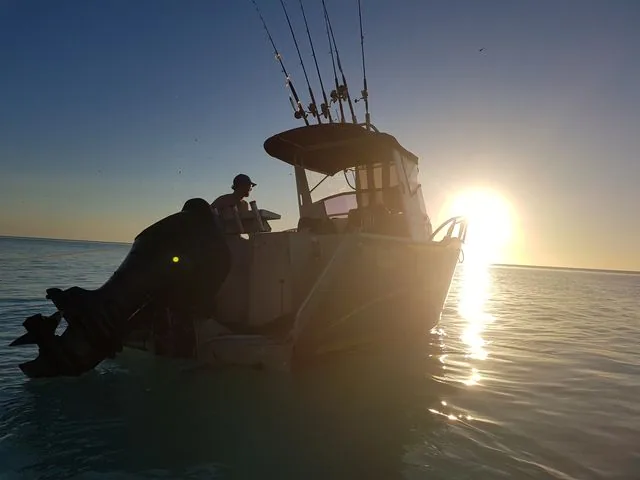 Fishing boat silhouetted against a low sun on the water