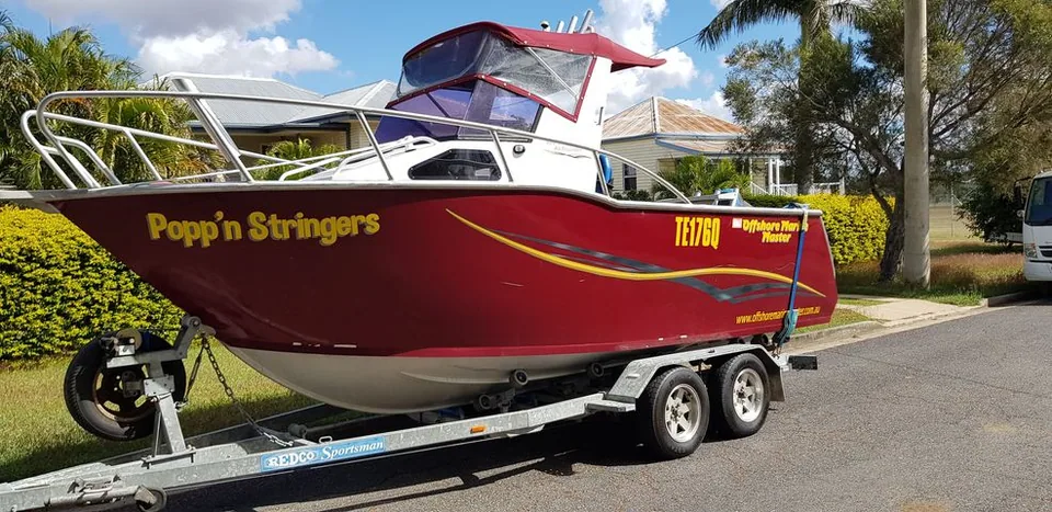 Red soft top boat with yellow hull graphics on a tandem-axle trailer