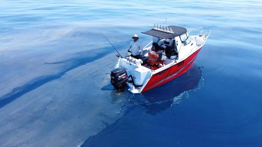 Red cabin boat photographed from above on calm blue water