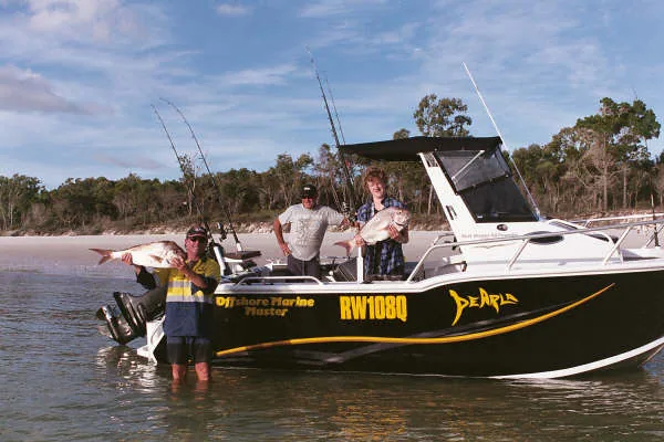 Three anglers displaying their catch beside a black-and-yellow boat