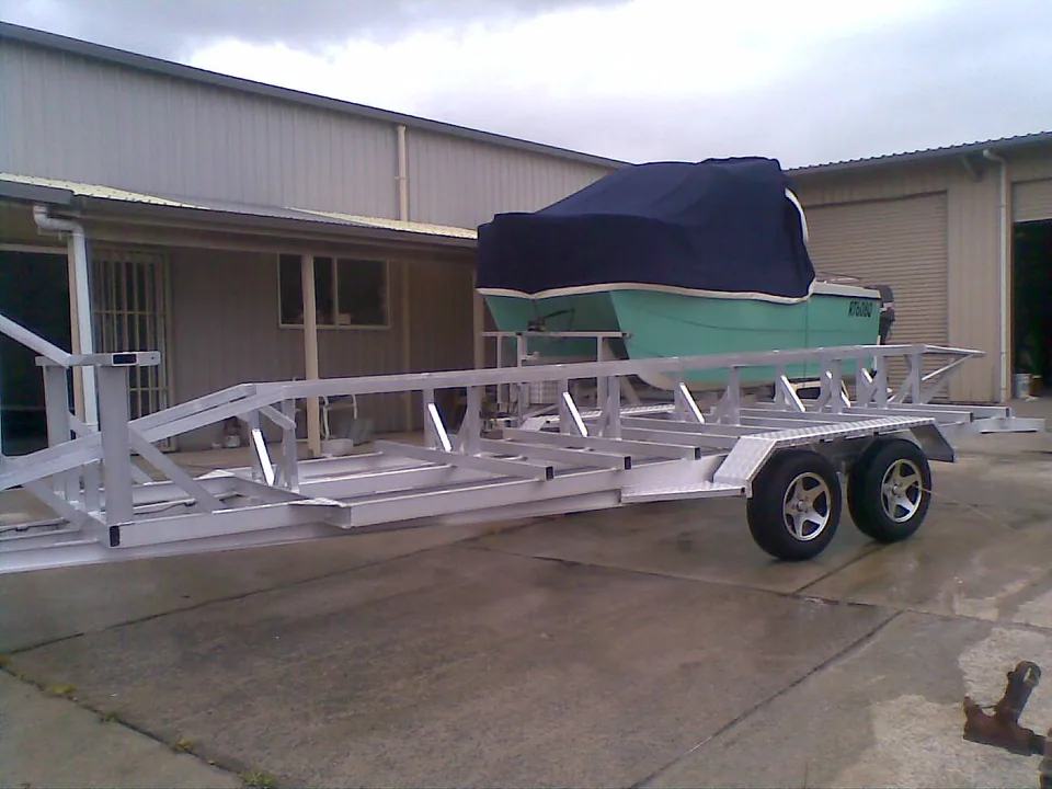 Bare tandem-axle alloy trailer frame outside the workshop