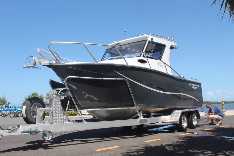 Black hardtop boat on a tandem-axle trailer beside the boat ramp