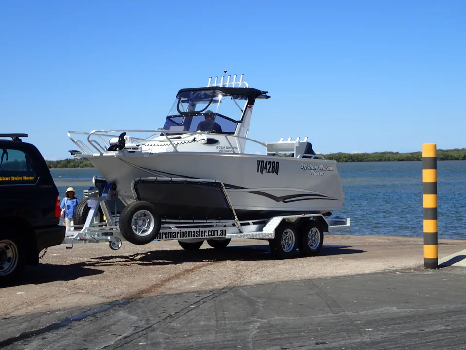 Grey cabin boat on a trailer beside a towing vehicle