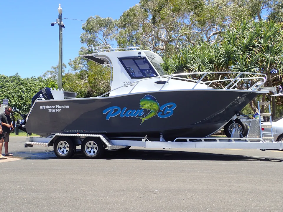 Dark hardtop boat with Plan B hull artwork on a trailer