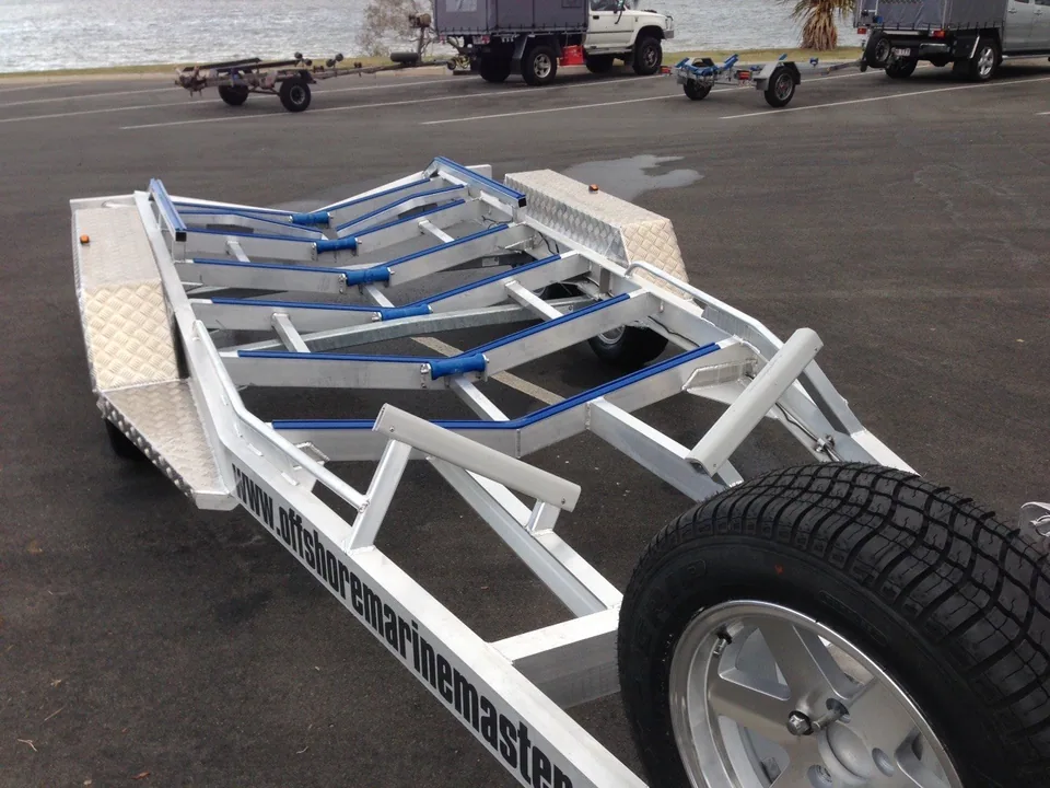 Angled view of an alloy trailer frame with blue rollers and spare tyres