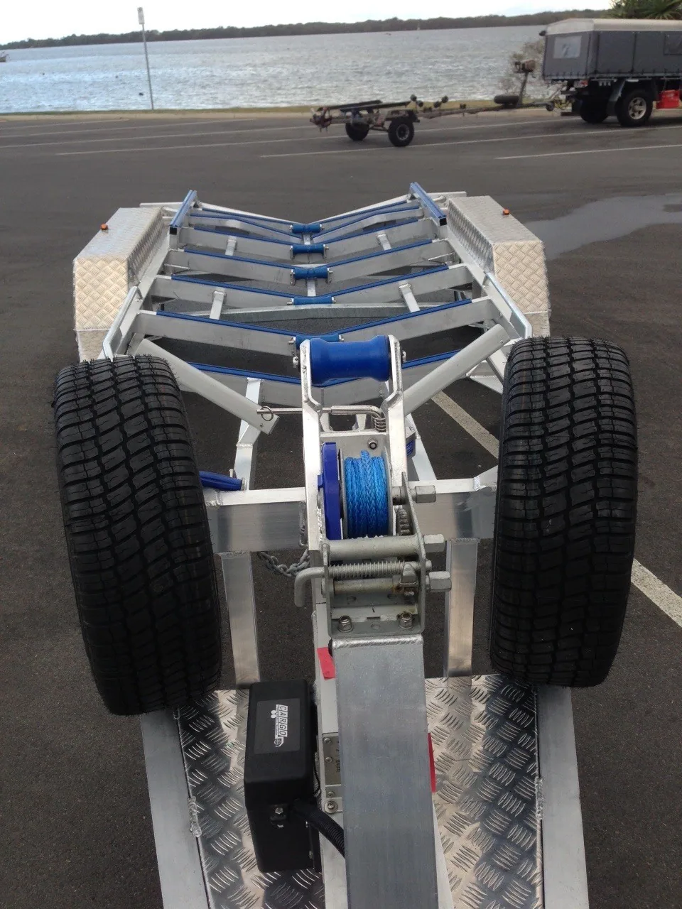 View along a boat trailer showing blue rollers and two spare tyres