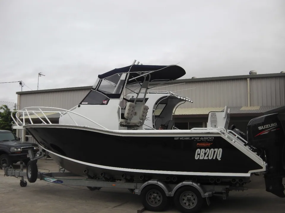 Black soft top boat with a raised helm and outboard on a trailer