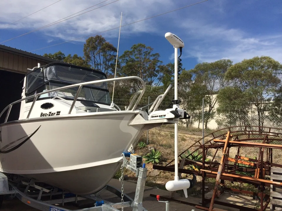 Bow-mounted electric motor on a white boat outside the workshop