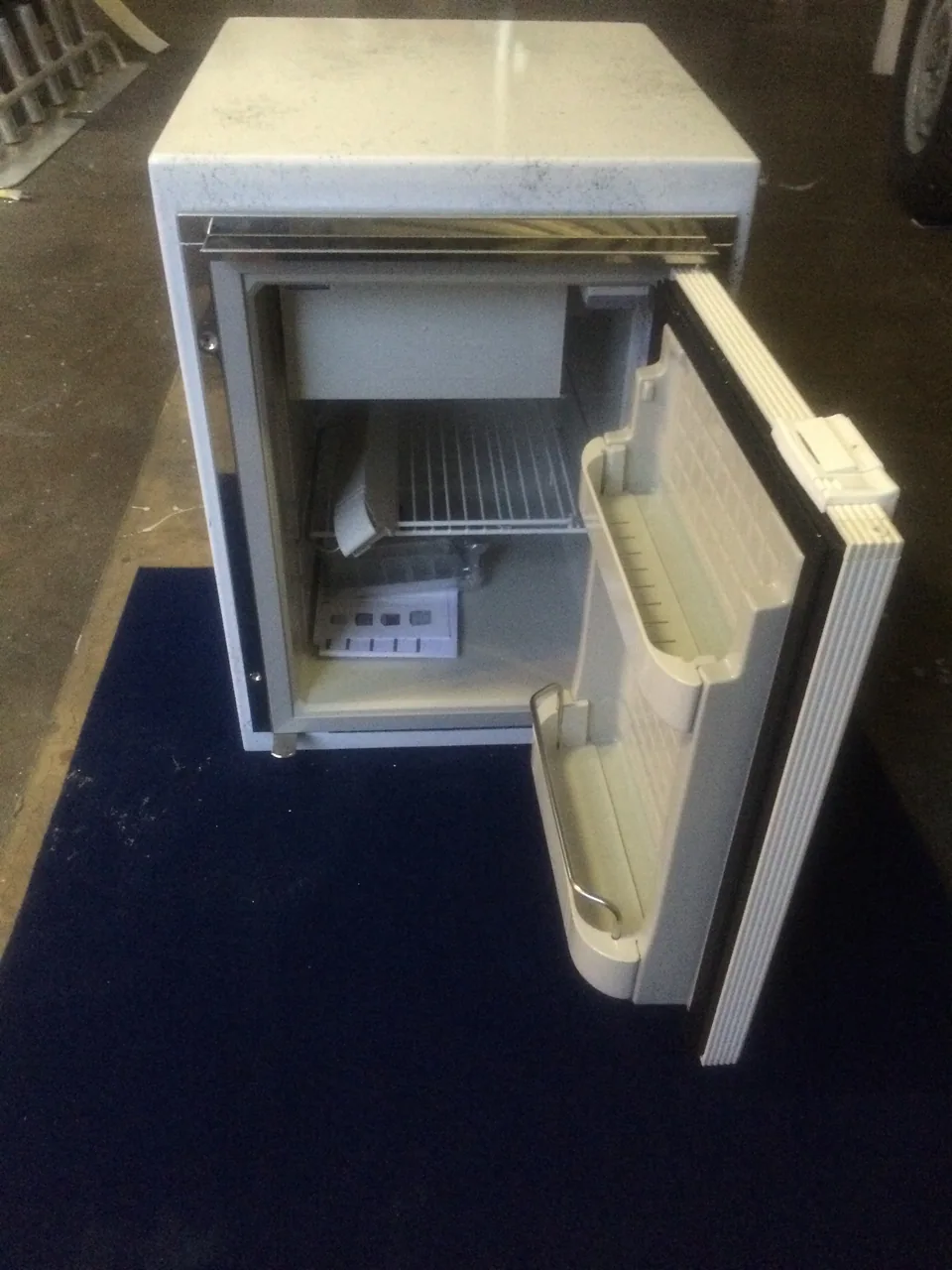 Compact refrigerator with its door open inside a fabricated cabinet